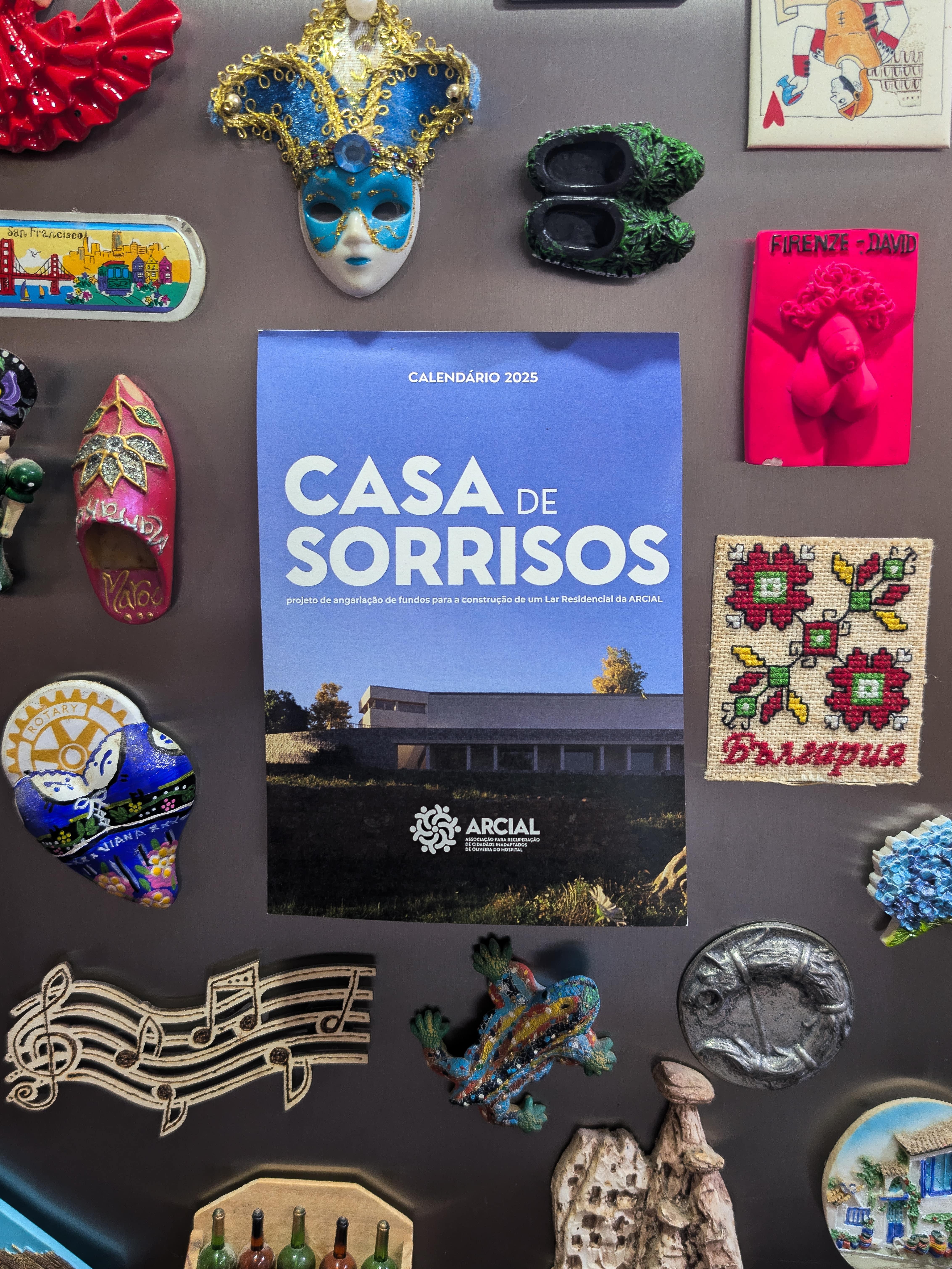 Picture of Casa de Sorrisos calendar cover on a fridge filled with magnets.