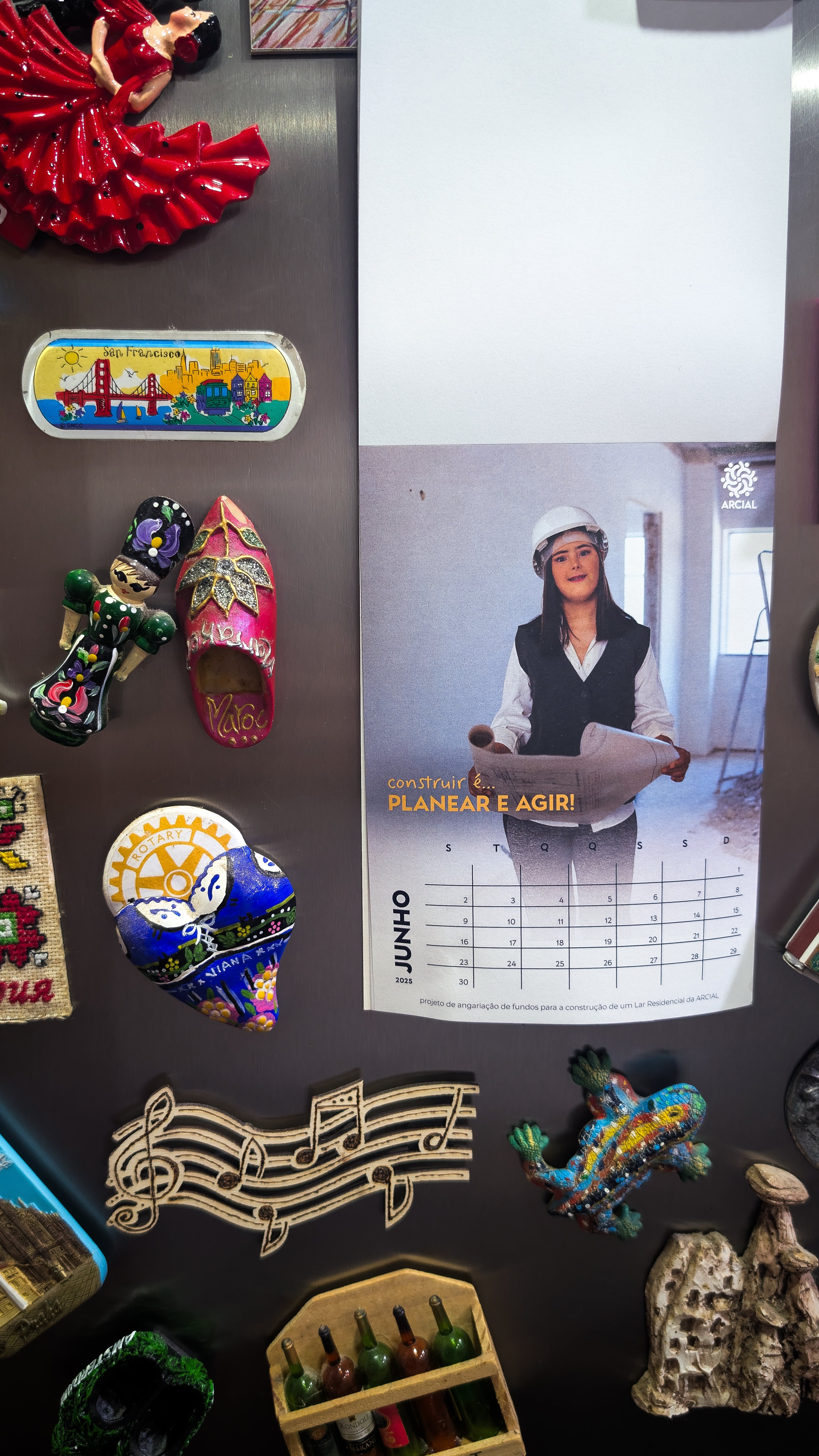 Picture for the July page of Casa de Sorrisos calendar, on a fridge filled with magnets.