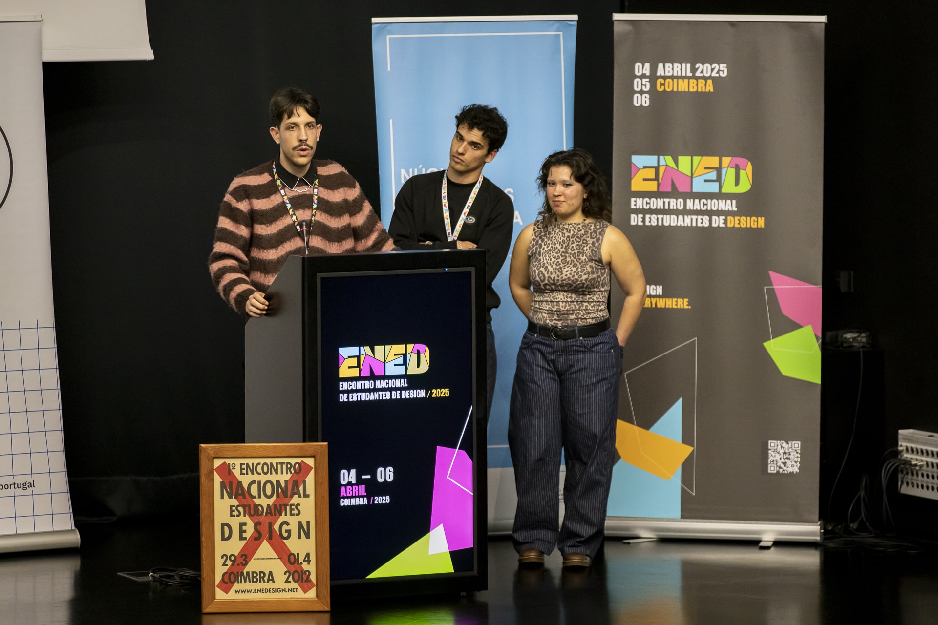 Picture of the three ENED general-coordinators, speaking on a stage.
